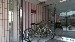 A bicycle parked in front of a building with a glass door and a sign on the wall. - Kyoto Plaza Hotel (Kyoto)