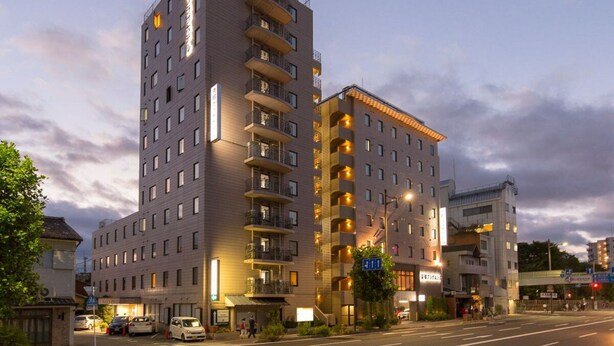 A multi-story hotel with balconies, a sign indicating a restaurant, and a pedestrian walkway. - Kyoto Plaza Hotel (Kyoto)