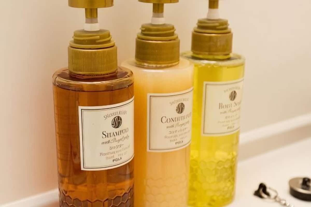Trois bouteilles de shampoing avec des pompes, posées sur le comptoir d’une salle de bain.