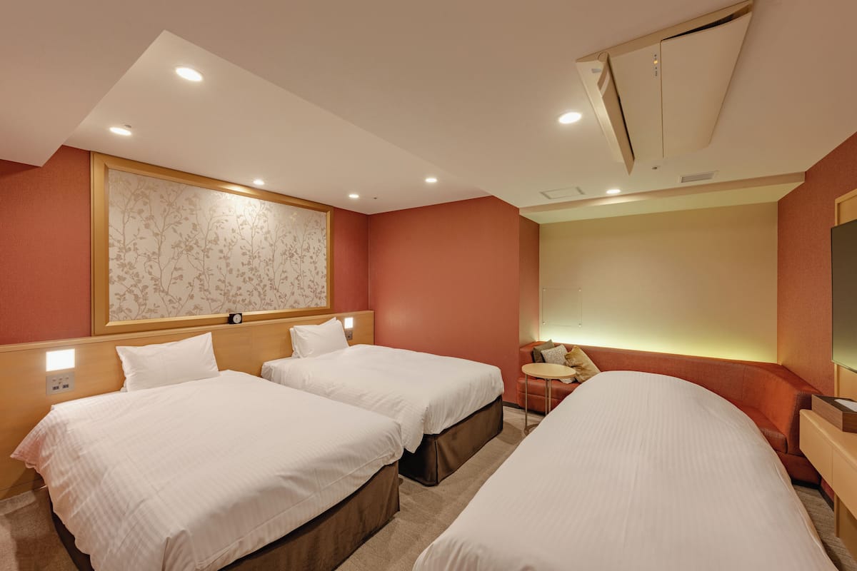 A hotel room with two single beds, a small table, a chair, and a large mirror.