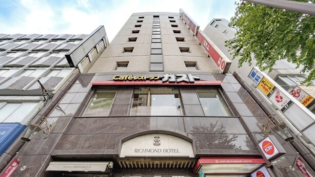 A hotel with a modern facade, a visible restaurant named 'Cafe Restaurant Gusto' on the ground floor, and a sign for 'Richmond Hotel' above the entrance.