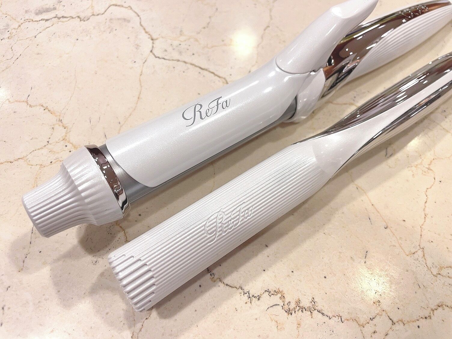 Two white pens with "BeFo" engraved on them, lying on a marble surface.