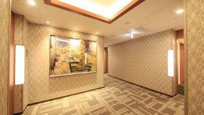 A hotel hallway with patterned walls, a bench, and a framed artwork on the wall.