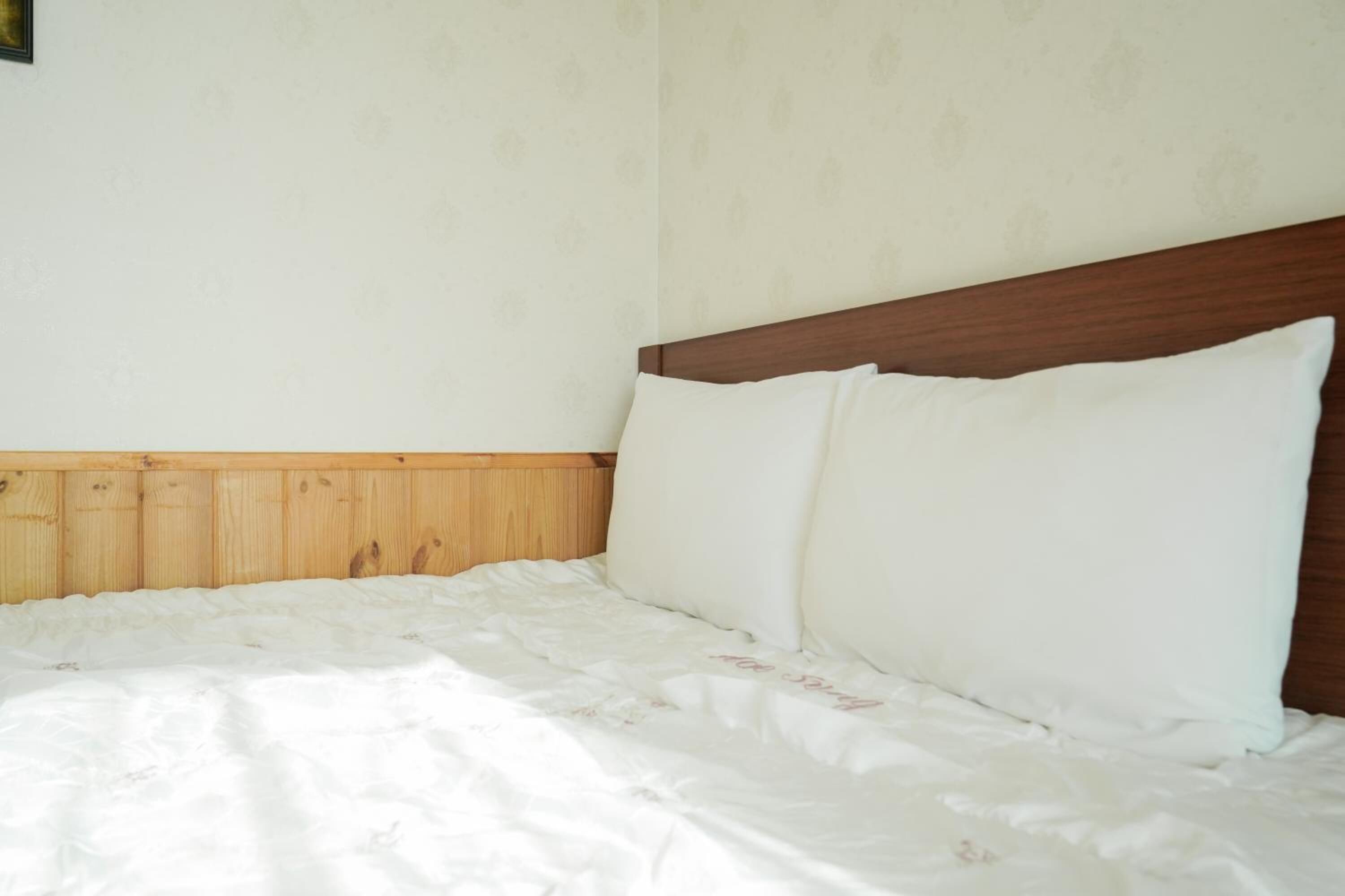 Un letto ben rifatto con lenzuola bianche e una testiera in legno.
