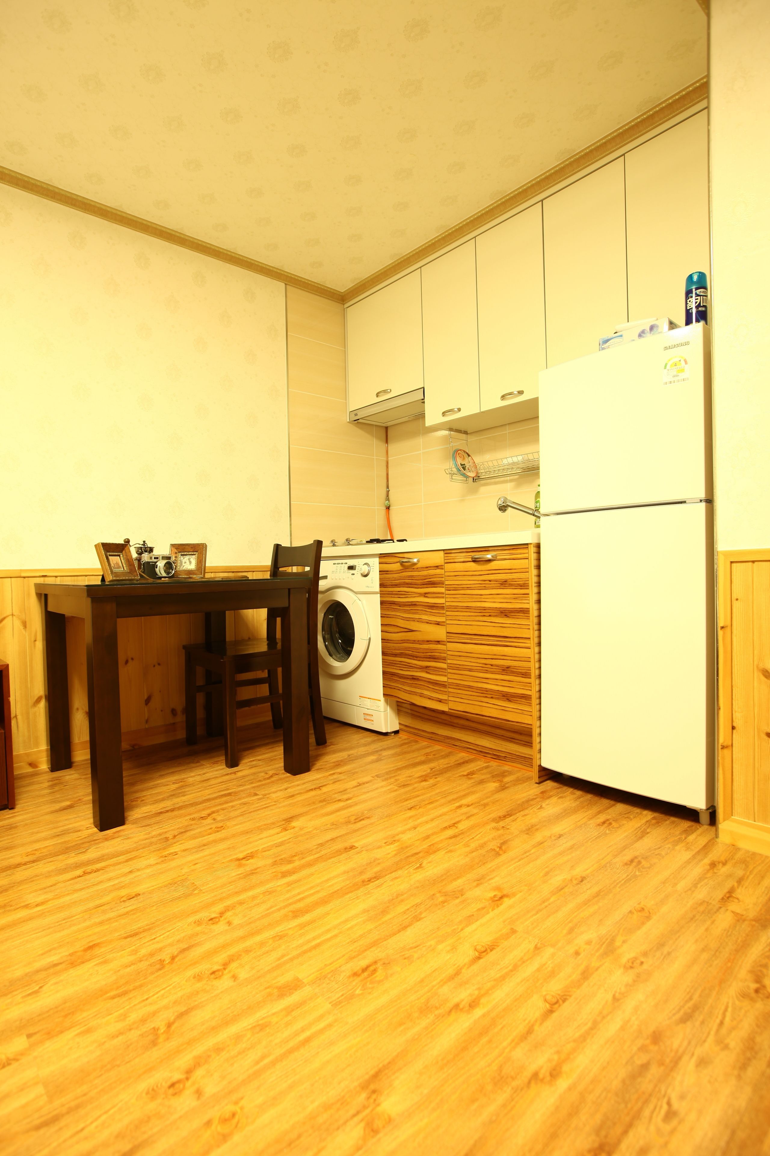 Een compacte keuken met houten kastjes, een wasmachine en een koelkast.