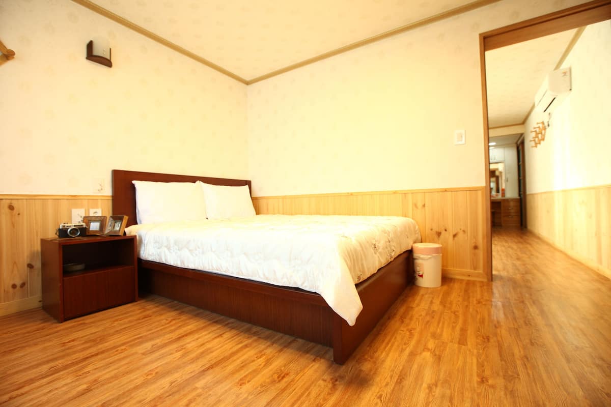 A bedroom with a wooden bed, a nightstand, and a small shelf with personal items.