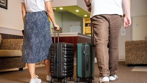 Un vestíbulo de hotel con un sofá, un mostrador de recepción y dos maletas.