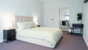 Un dormitorio moderno con cama, mesitas de noche, un escritorio y una silla.
