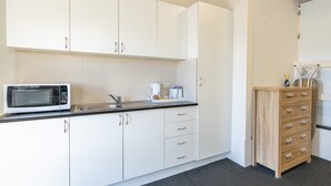 Una cocina moderna con armarios blancos, microondas, pileta y un mueble de madera con cajones.
