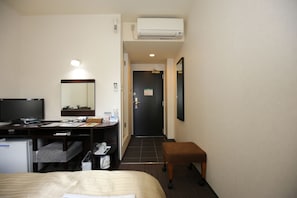 A hotel room with a bed, desk, chair, and a small table. There is a television, a mirror, and an air conditioning unit. - Kyoto Plaza Hotel Annex (Kyoto)