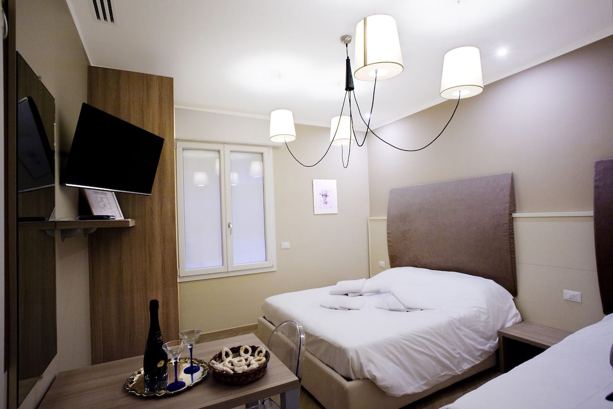 Una habitación de hotel con cama, mesita de noche y televisor montado en la pared.
