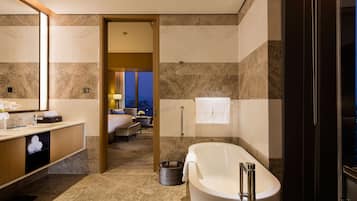 A modern hotel bathroom with a large bathtub, a vanity with a mirror, and a shower area.