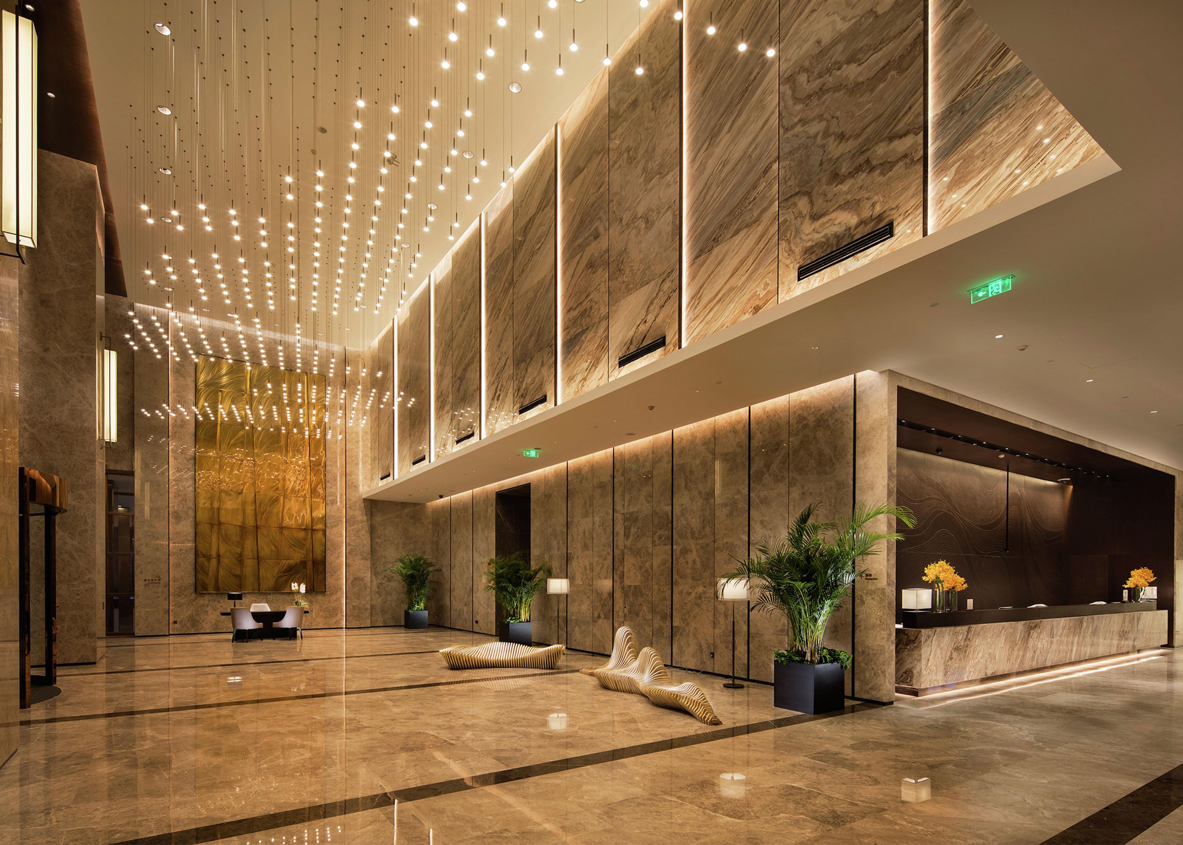 Un hall d’entrée moderne avec un plafond haut, des murs en marbre et un comptoir d’accueil.