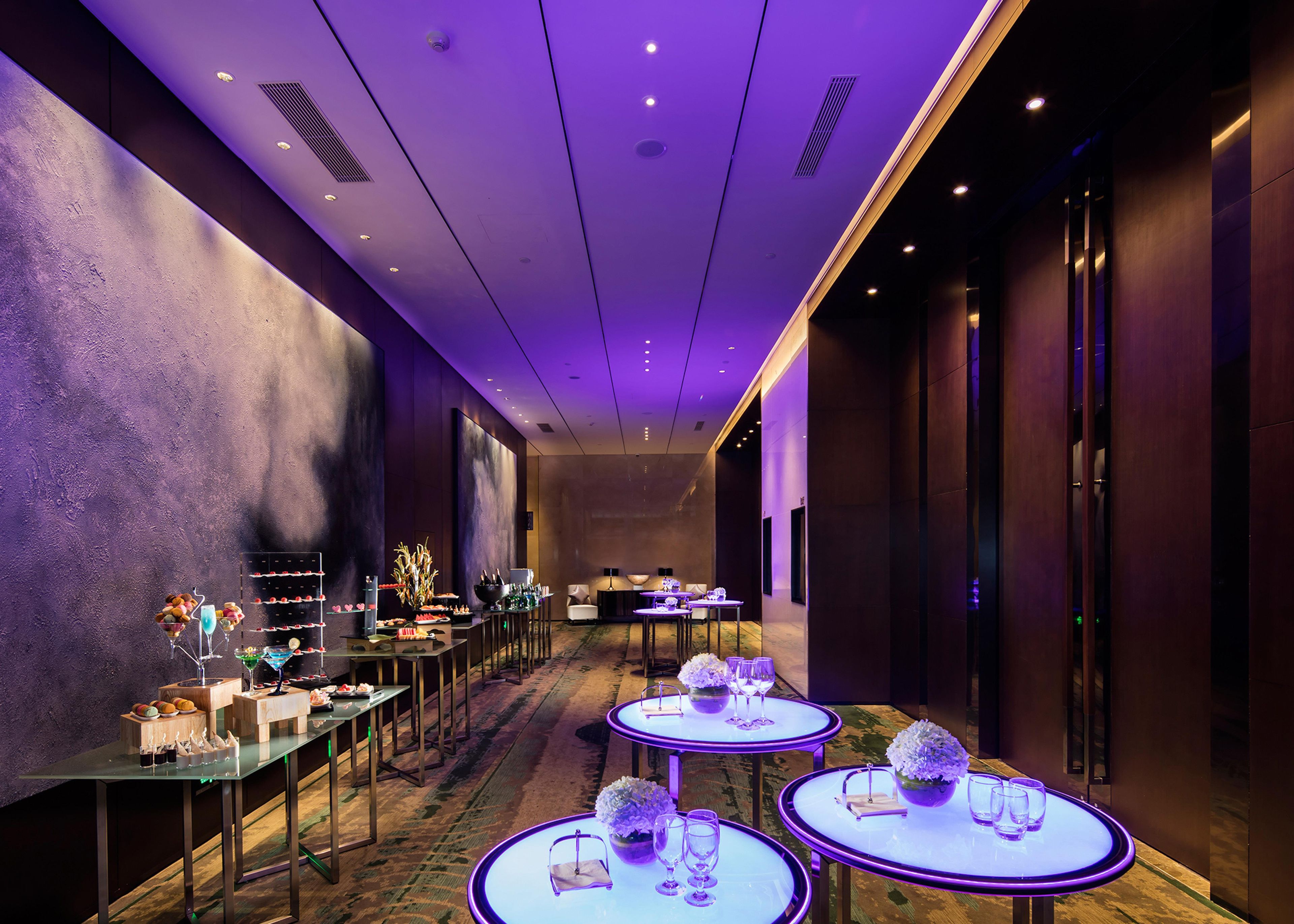A hotel corridor with tables set for dining, a reception area, and a modern interior design.