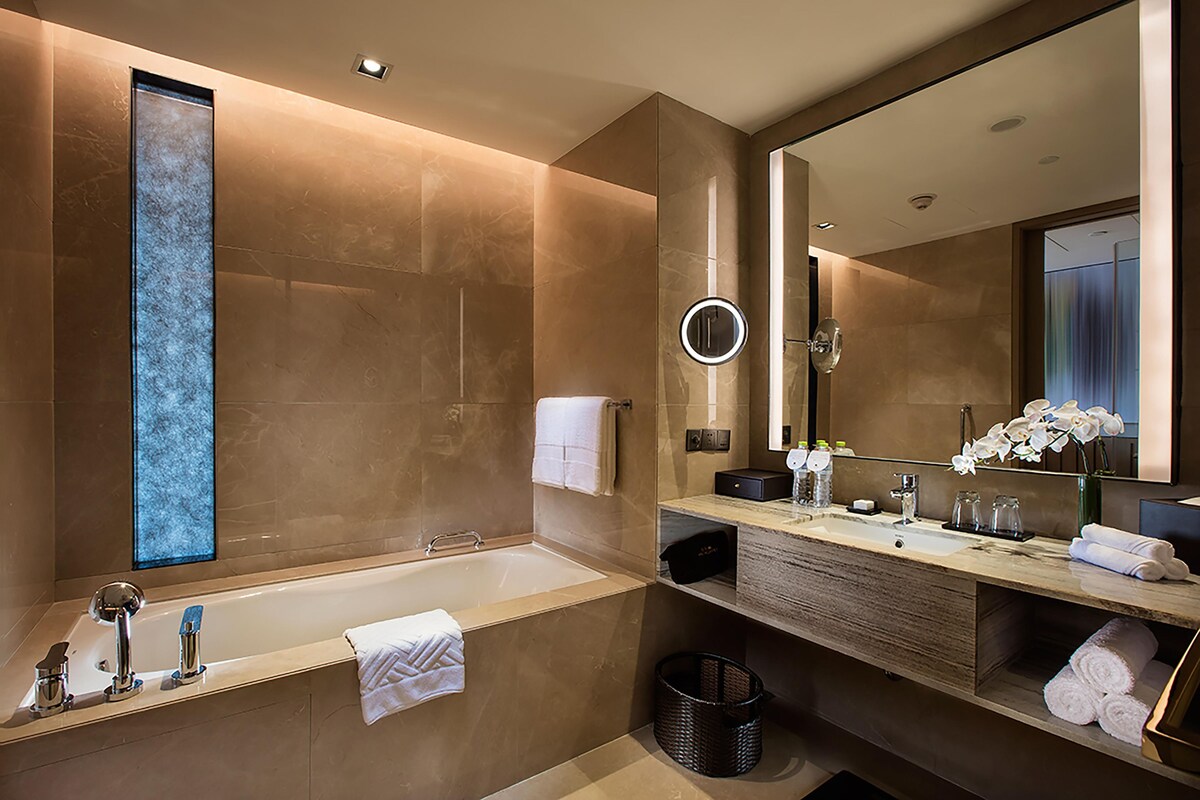 Un baño moderno con una bañera grande, un tocador con espejo y una ventana con vistas.