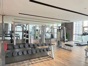 Un gimnasio moderno con diversos equipos de ejercicio, como mancuernas, cinta de correr y máquinas de pesas.