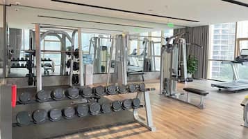A modern gym with various exercise equipment, including dumbbells, a treadmill, and weight machines.