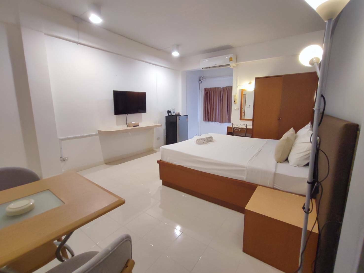 Una habitación de hotel con una cama, un escritorio, una silla, un televisor y un armario.