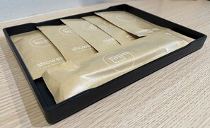 A black box with four brown paper bags labeled 'shower' on a wooden surface.