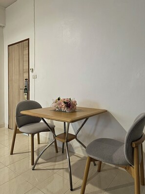 A dining area with a wooden table, two grey chairs, and a floral centerpiece.