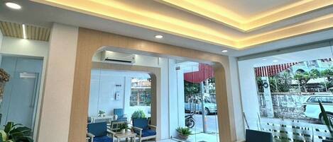 A modern lobby with seating, a reception desk, and a view of the street.