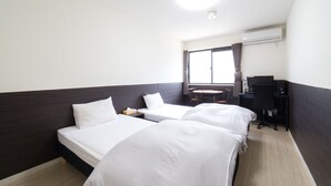 Ein Hotelzimmer mit zwei Betten, einem Schreibtisch und einem Fenster mit Vorhängen.