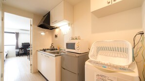 Eine kompakte Küche mit Mikrowelle, kleinem Kühlschrank und Waschmaschine.