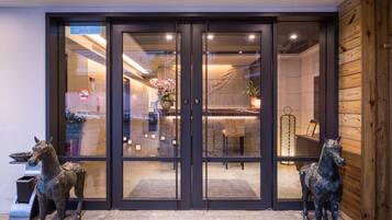 A hotel entrance with a glass door, two horse statues, and a wooden wall.