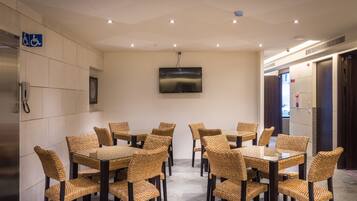 A conference room with multiple tables and chairs, a mounted television, and a handicap accessible sign on the wall.