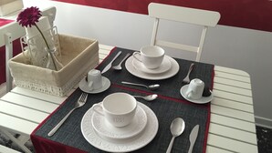 A neatly set dining table with white tableware and a vase with a single flower. - Domus Mea- Adults Only (Verona)