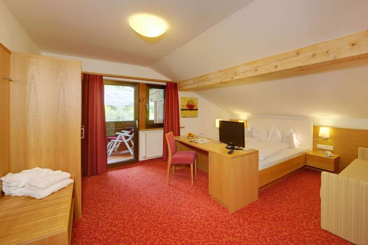 Une chambre d’hôtel équipée d’un lit, d’un bureau, d’une chaise et offrant une vue sur l’extérieur.