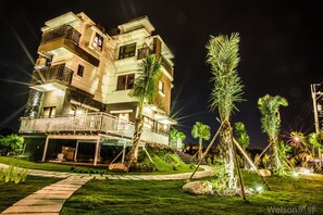 A multi-story hotel with a balcony on the ground floor, surrounded by well-maintained lawns and palm trees. - Sofia Villa (Dongshan)