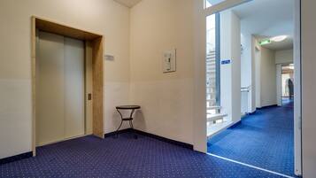 A hallway with a blue carpet, a wooden door, and a small table.