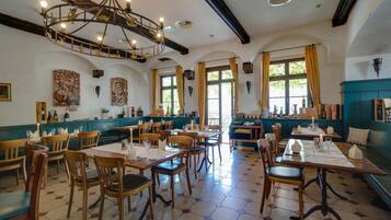 A restaurant with hexagonal patterned flooring, wooden tables and chairs, and a chandelier with hanging light fixtures.