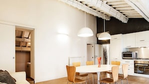 A modern kitchen with white cabinets, a dining table with chairs, and a built-in oven. - At Home Spanish Steps (Rome)