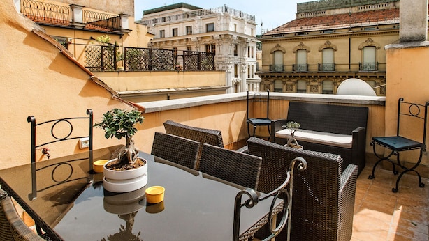 A rooftop terrace with a dining table, wicker chairs, and a potted plant. - At Home Spanish Steps (Rome)