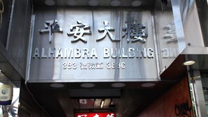 Un edificio con letrero que indica 'ALHAMBRA BUILDING' y un número de contacto.