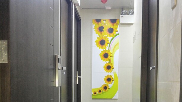 Un pasillo con puertas de madera oscura, suelo de baldosas y un cuadro de girasoles colgado en la pared.