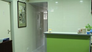 Un pasillo con una recepción, una obra de arte enmarcada en la pared y una puerta que da a otra habitación.