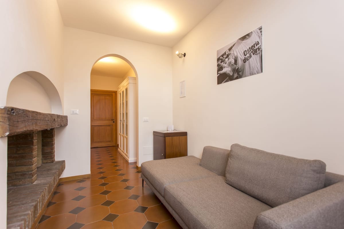 Un salon moderne avec un canapé, une cheminée et un couloir menant à une porte en bois.