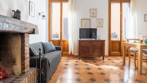 Ein Wohnzimmer mit Kamin, einer Couch, einem Fernseher und einem Essbereich mit Tisch und Stühlen.