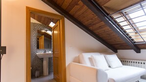 Ein weißes Sofa in einem Raum mit geneigter Decke und einem Oberlicht.