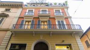 Ein Gebäude mit einem großen Bogenportal, einem Balkon mit schmiedeeisernen Geländern und einem Geschäft mit einem gelben Schild.