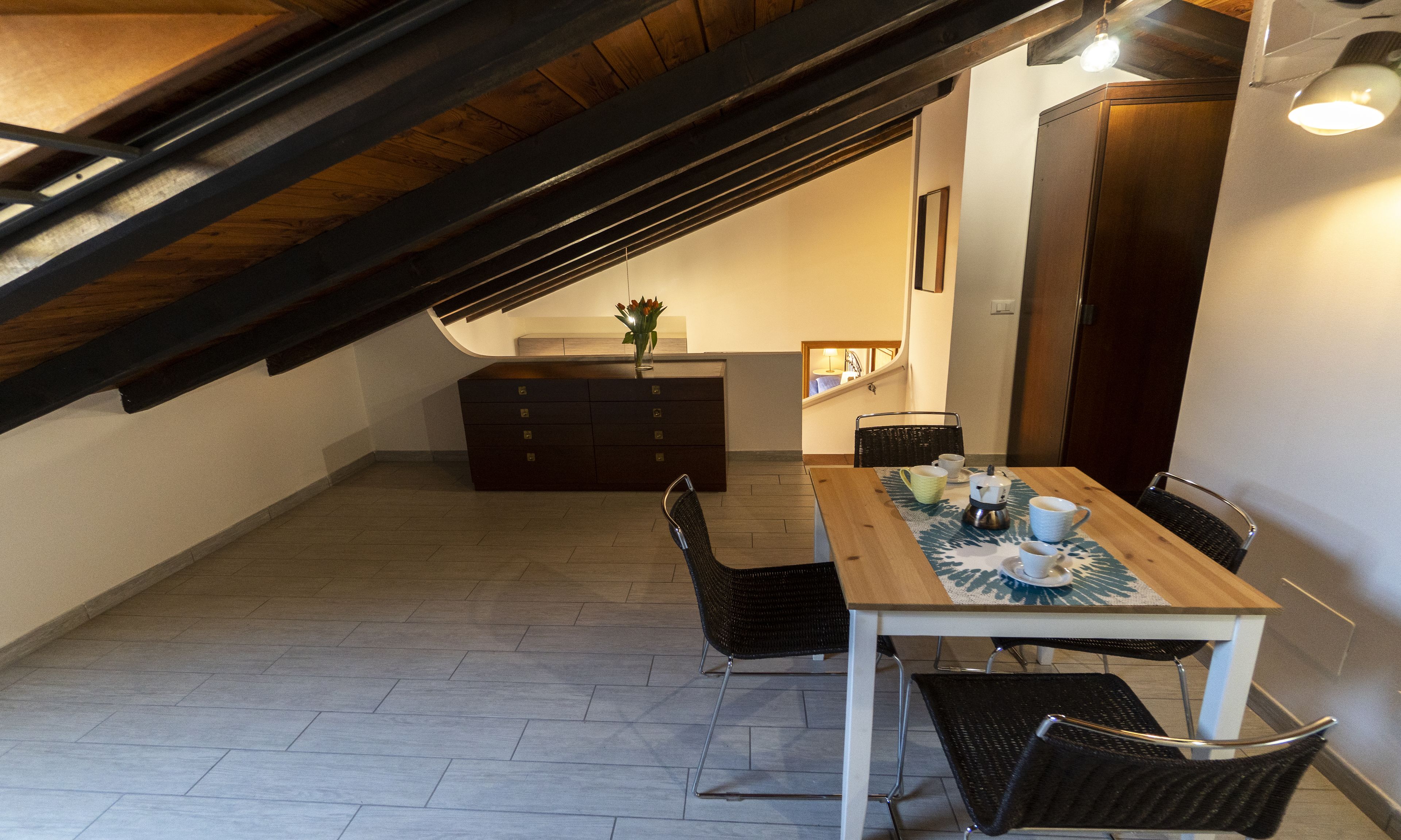 A dining area with a wooden table, chairs, and a kitchen in the background.