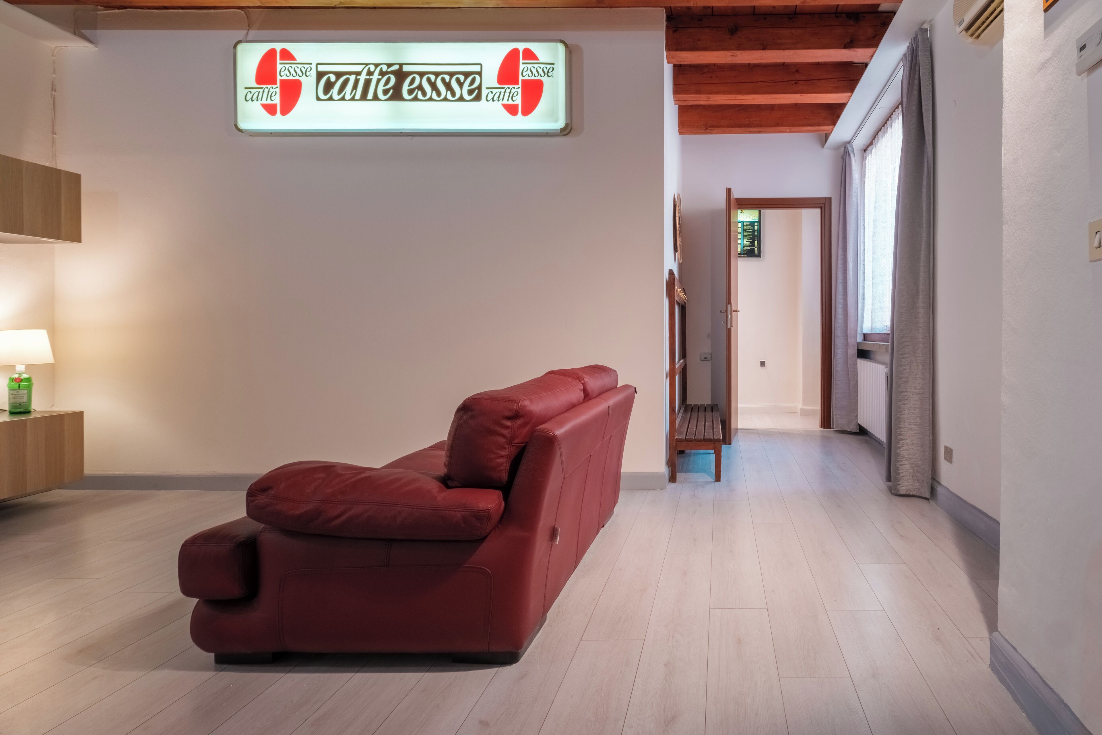 Un sofá de cuero rojo en un pasillo, con un letrero que dice 'café esse'.