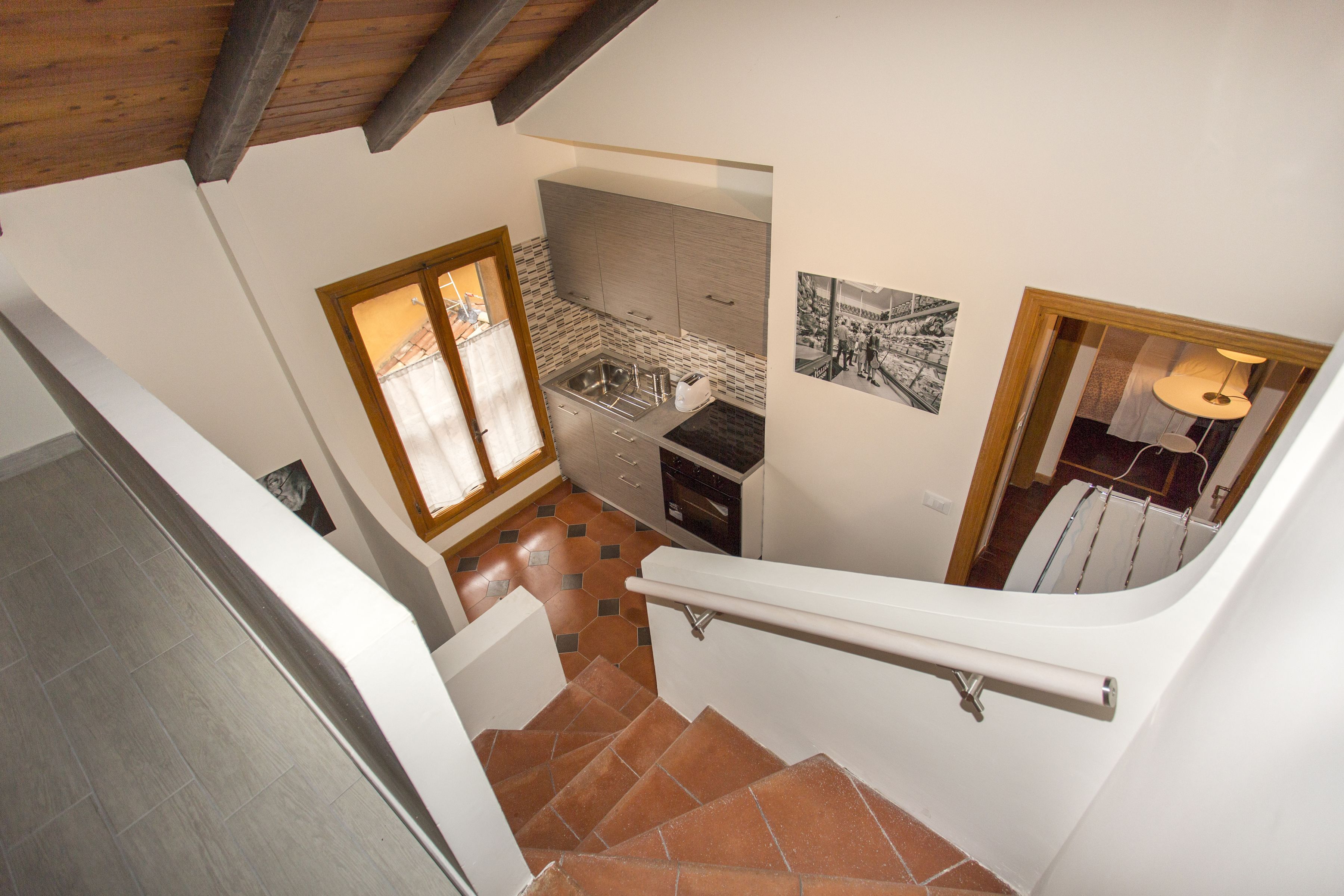 A staircase leading to a kitchen with a tiled floor, a window, and a sink.