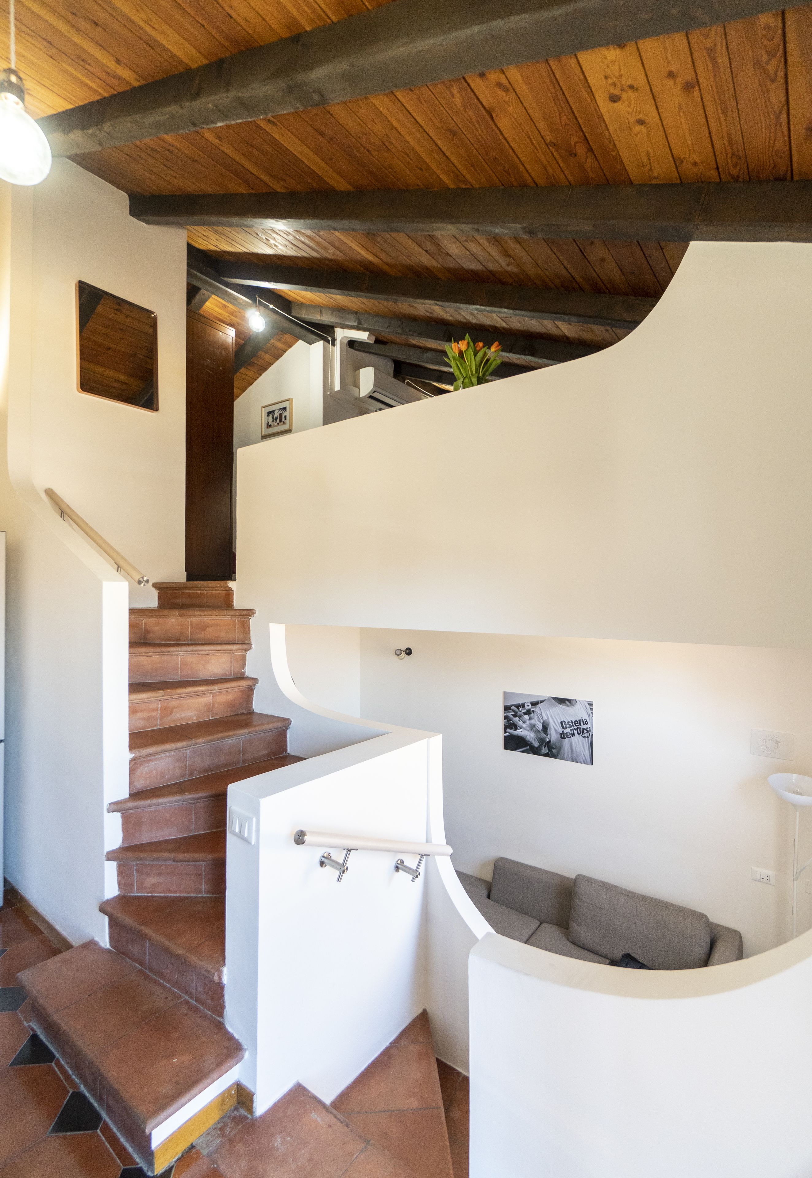 Eine Treppe führt zu einem Schlafzimmer auf dem Dachboden, mit einer eingebauten Schlafcouch und einem kleinen Tisch.