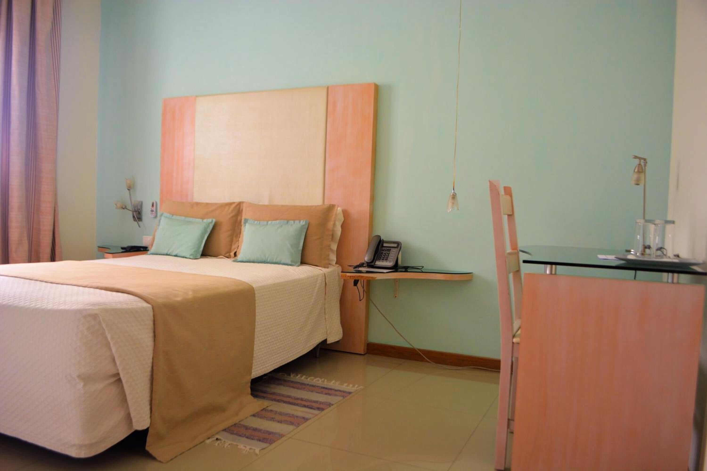 Ein Hotelzimmer mit Bett, Nachttisch, Lampe und Schreibtisch mit Stuhl.