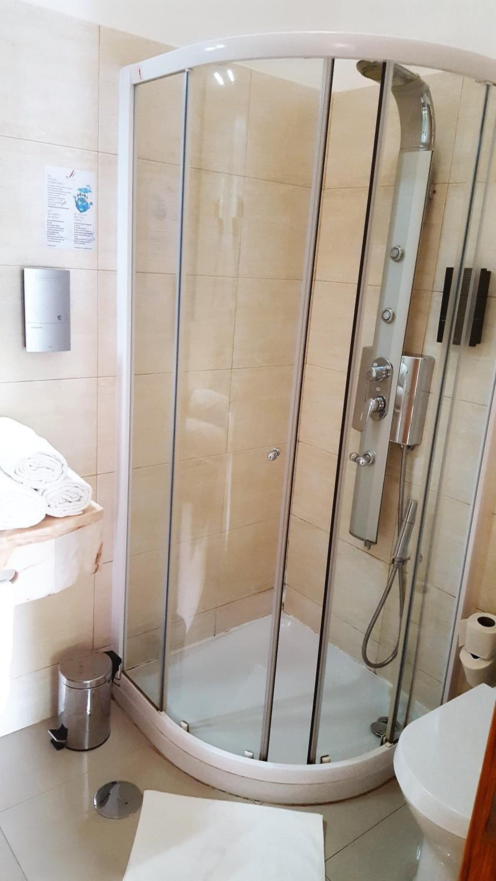 A glass-enclosed shower stall with a handheld showerhead and a wall-mounted faucet.