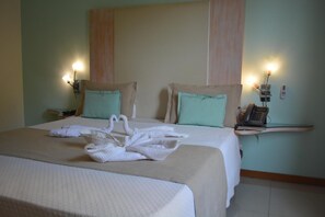 A hotel room with two beds, a bedside telephone, and a wall-mounted lamp.